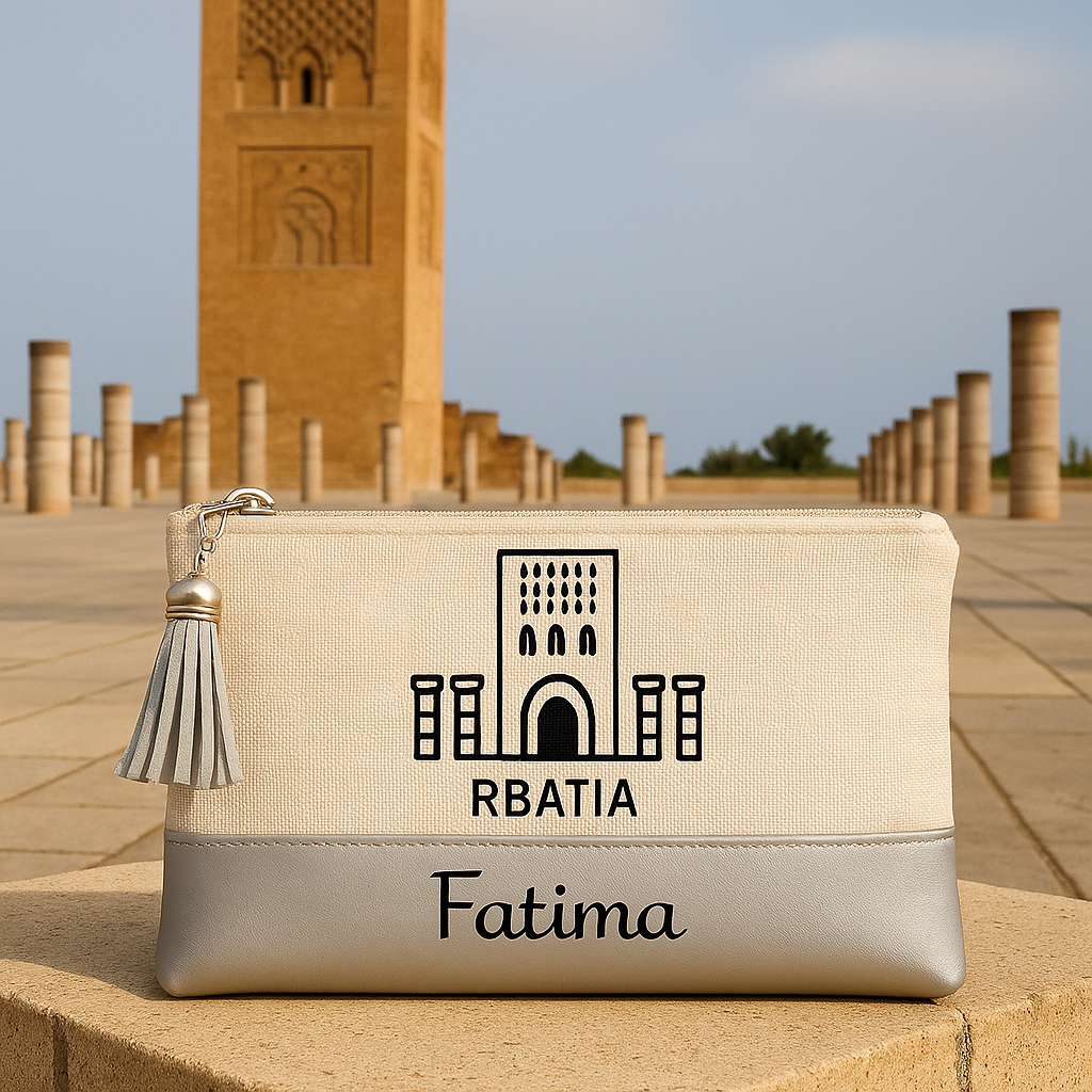 Pochette rbatia personnalisée posée devant la Tour Hassan à Rabat, avec prénom Fatima et pompon argenté.